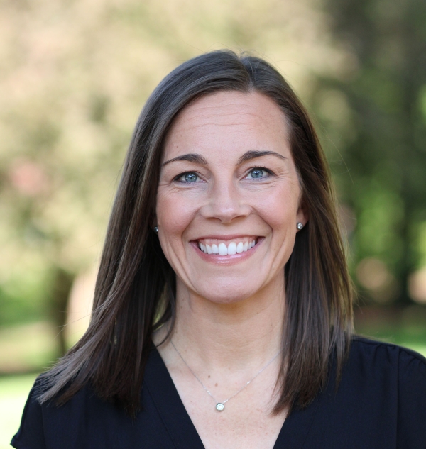 Meagan Bryson, a light-skinned woman with blue eyes and straight dark hair, smiles for a head shot.